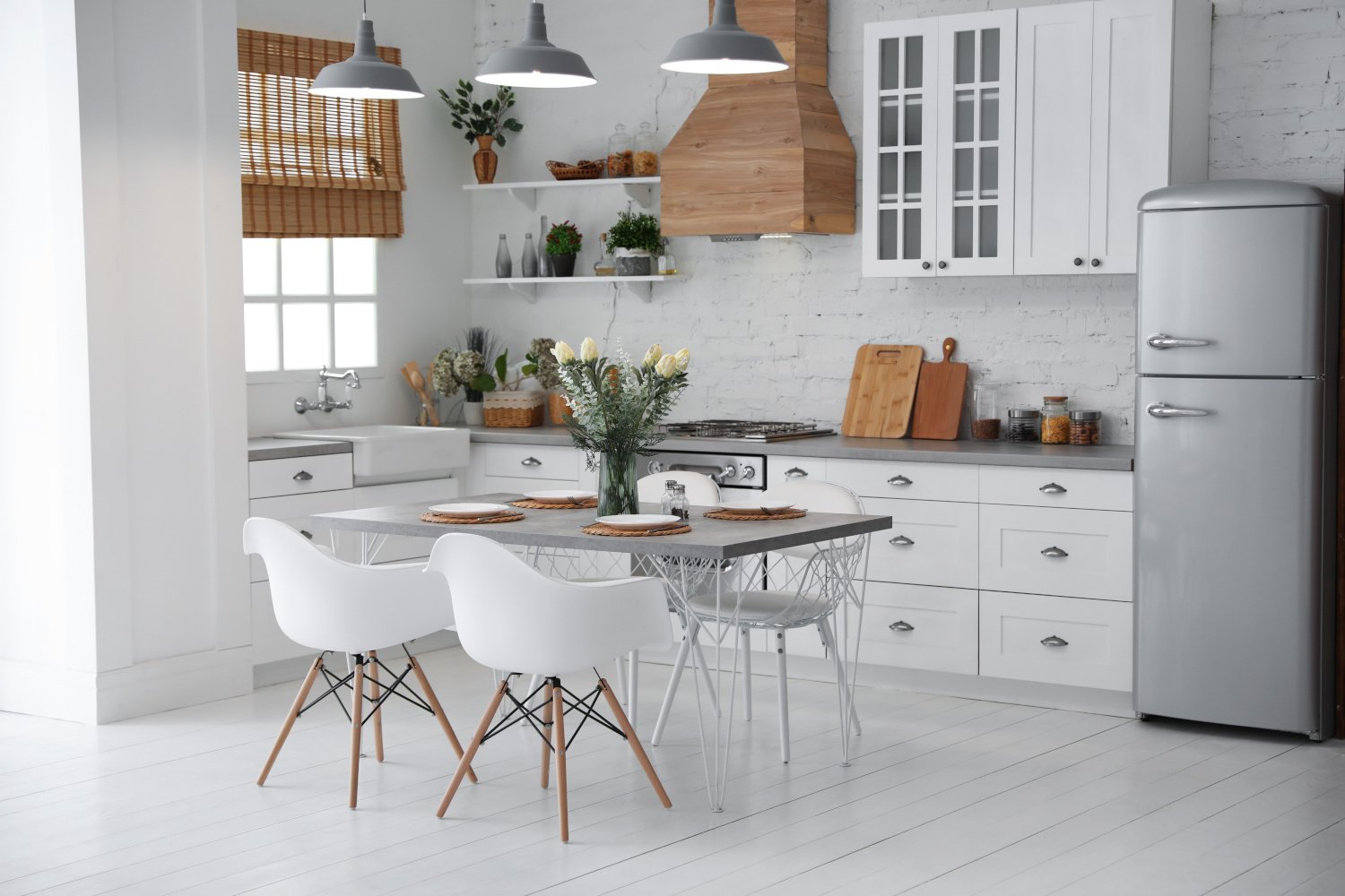 Modern all-white L-shaped kitchen with gray countertops and a white kitchen table